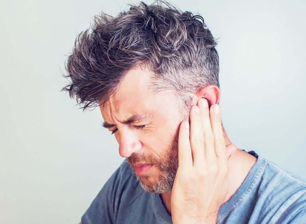 Man met tinnitus houdt zijn hand bij zijn pijnlijke oor